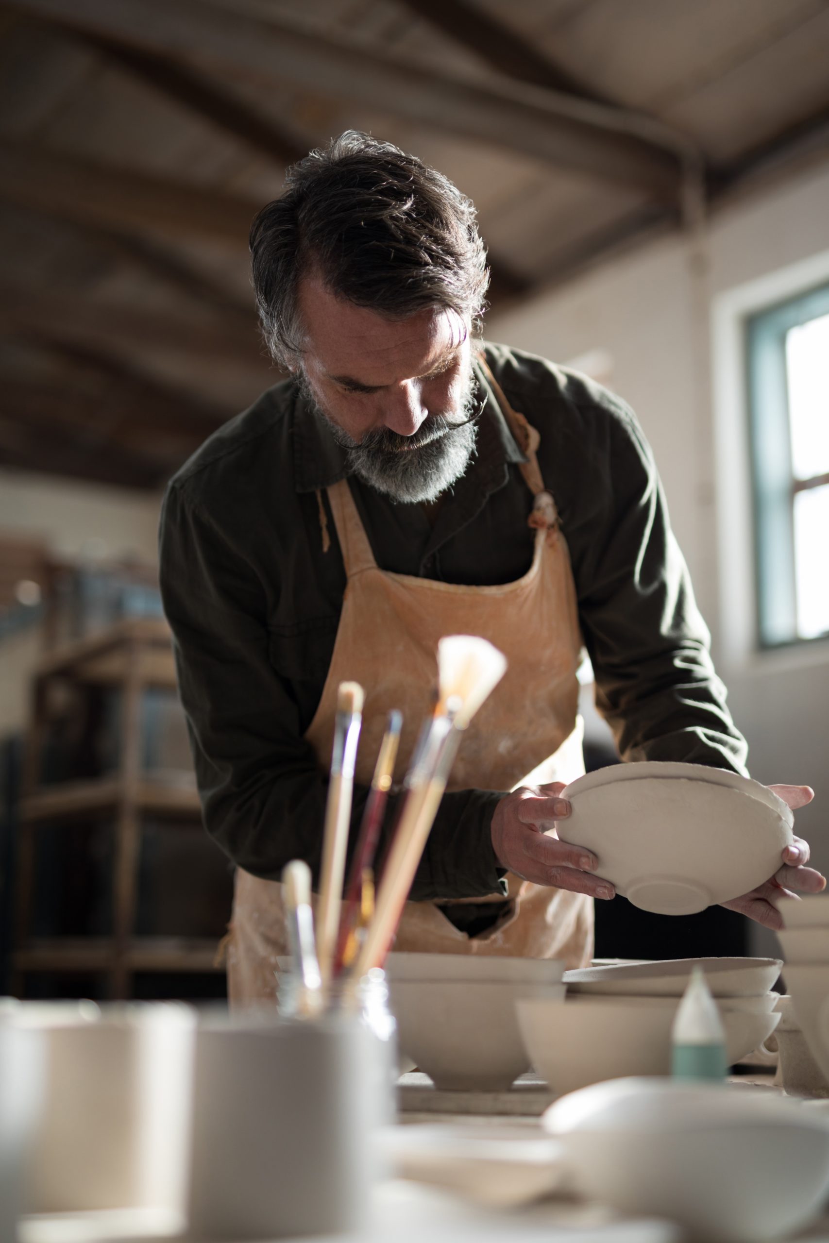 Male potter checking bowls at worktop